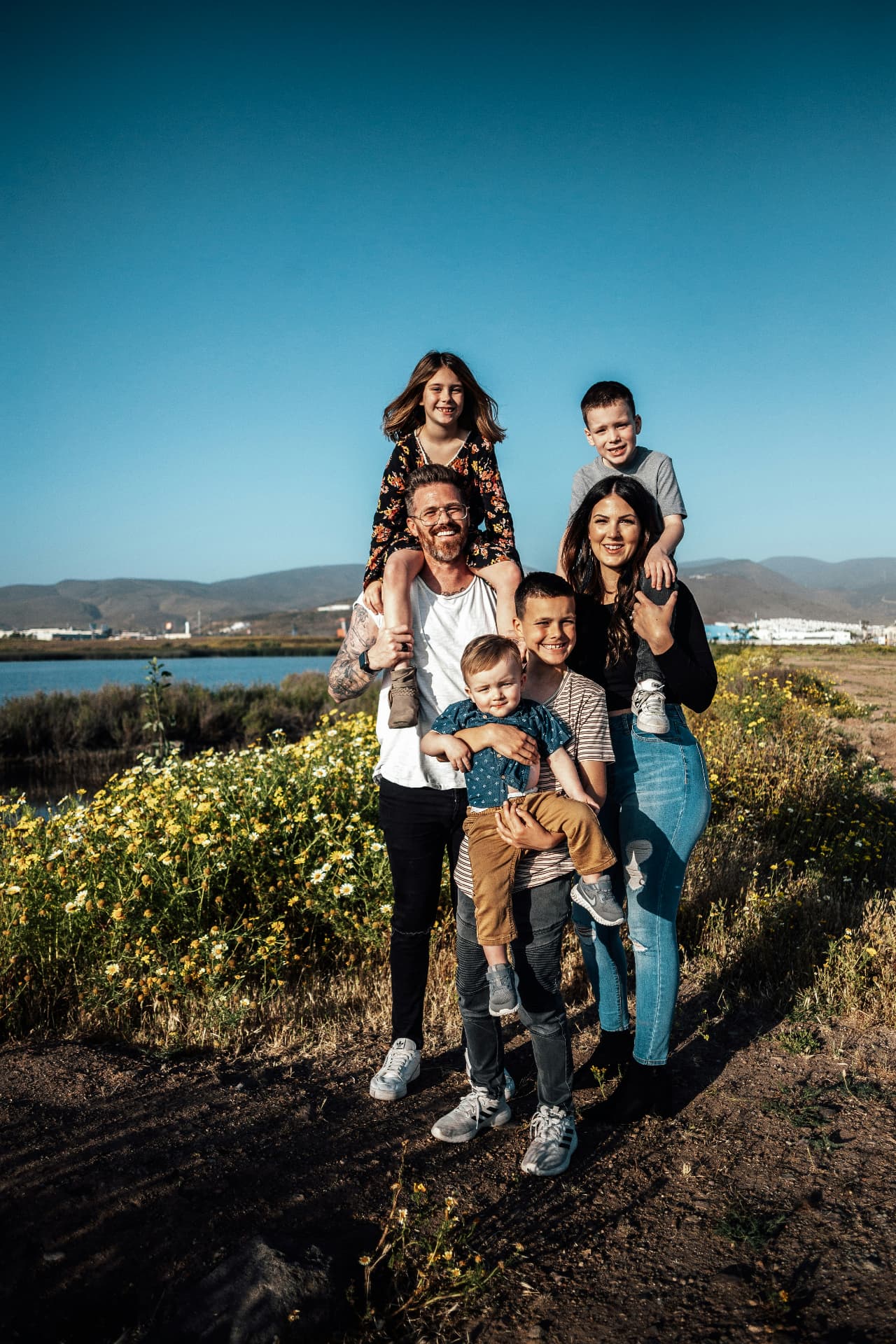 A military family of six standing together outdoors on a sunny day